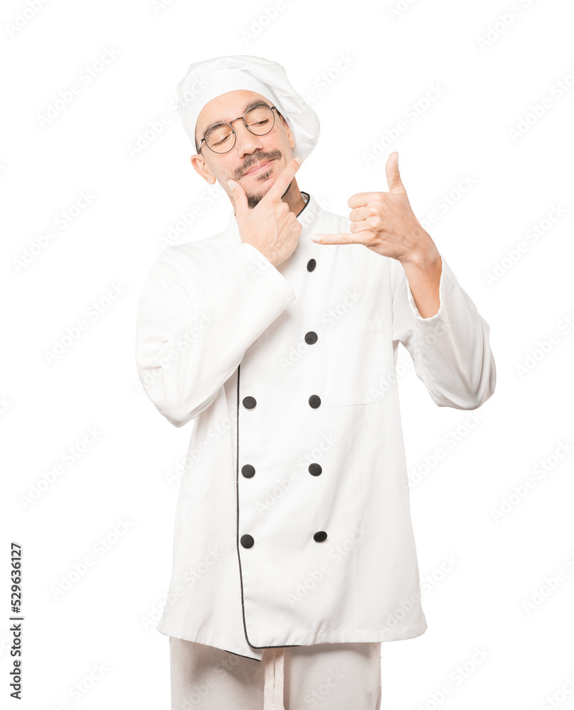Hesitant young chef making a gesture of calling with the hand Hesitant young chef making a gesture of calling with the hand