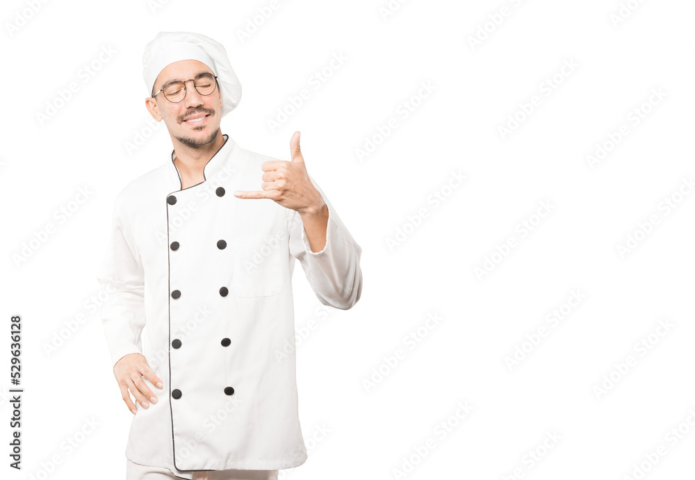 Happy young chef making a gesture of calling with the hand Happy young chef making a gesture of calling with the hand