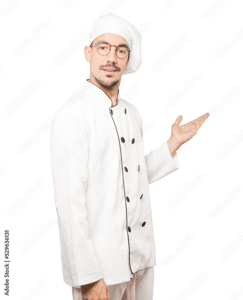 Amazed young chef making a gesture of welcome Amazed young chef making a gesture of welcome