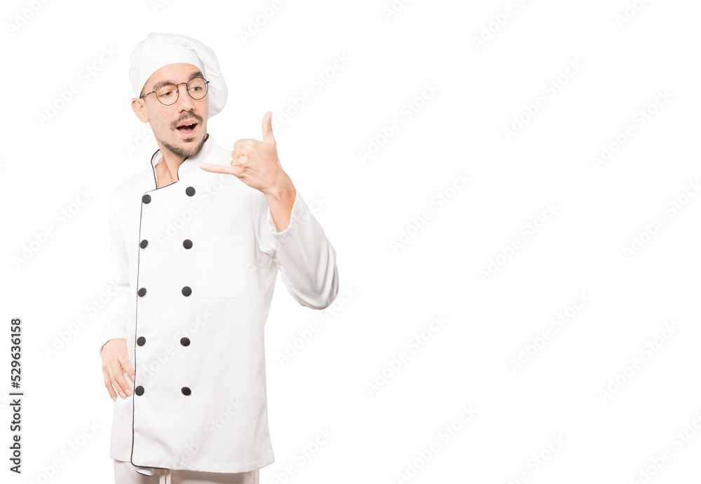 Amazed young chef making a gesture of calling with the hand Amazed young chef making a gesture of calling with the hand