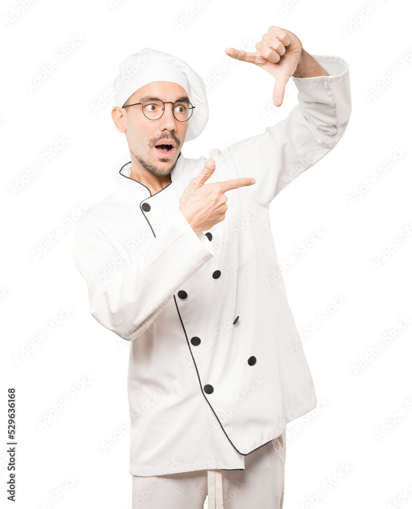 Amazed young chef making a gesture of taking a photo with the hands Amazed young chef making a gesture of taking a photo with the hands