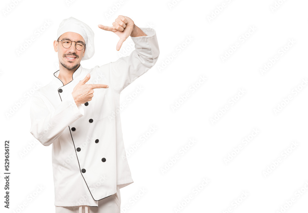 Friendly young chef making a gesture of taking a photo with the hands