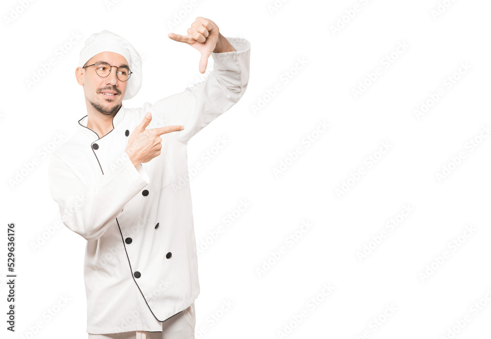 Amazed young chef making a gesture of taking a photo with the hands