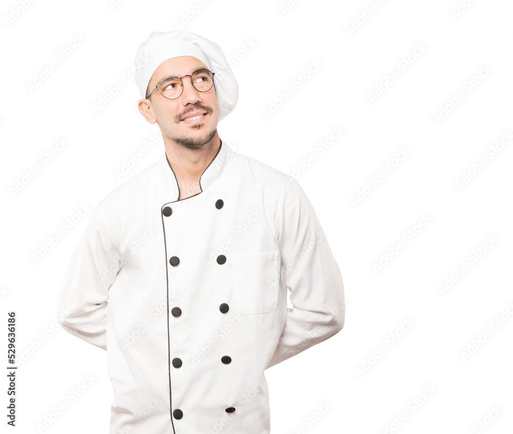 Happy young chef looking against background