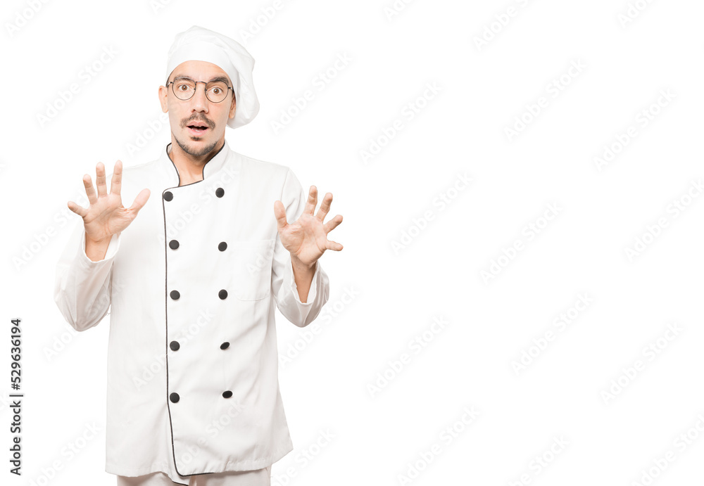 Scared young chef screaming against background Scared young chef screaming against background