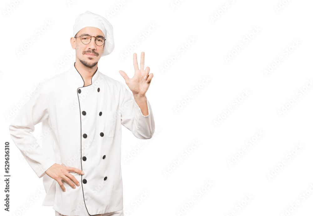 Young chef making a number three gesture
