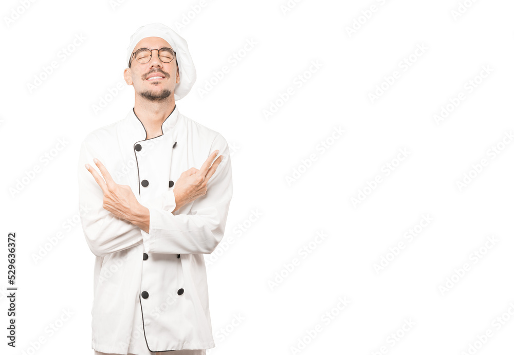 Happy young chef making a victory gesture with his fingers