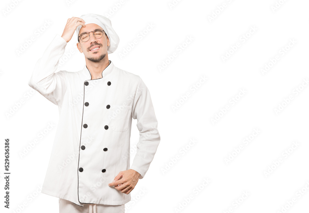 Concerned young chef making a scratching gesture Concerned young chef making a scratching gesture