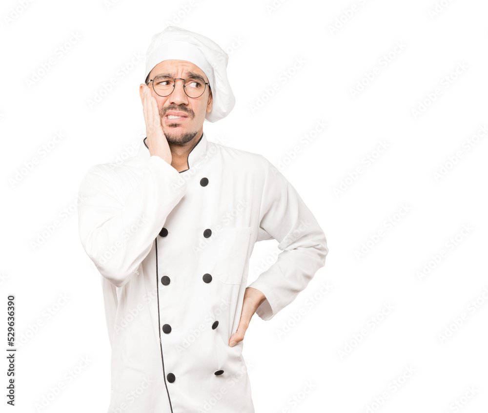 Concerned young chef posing against background Concerned young chef posing against background