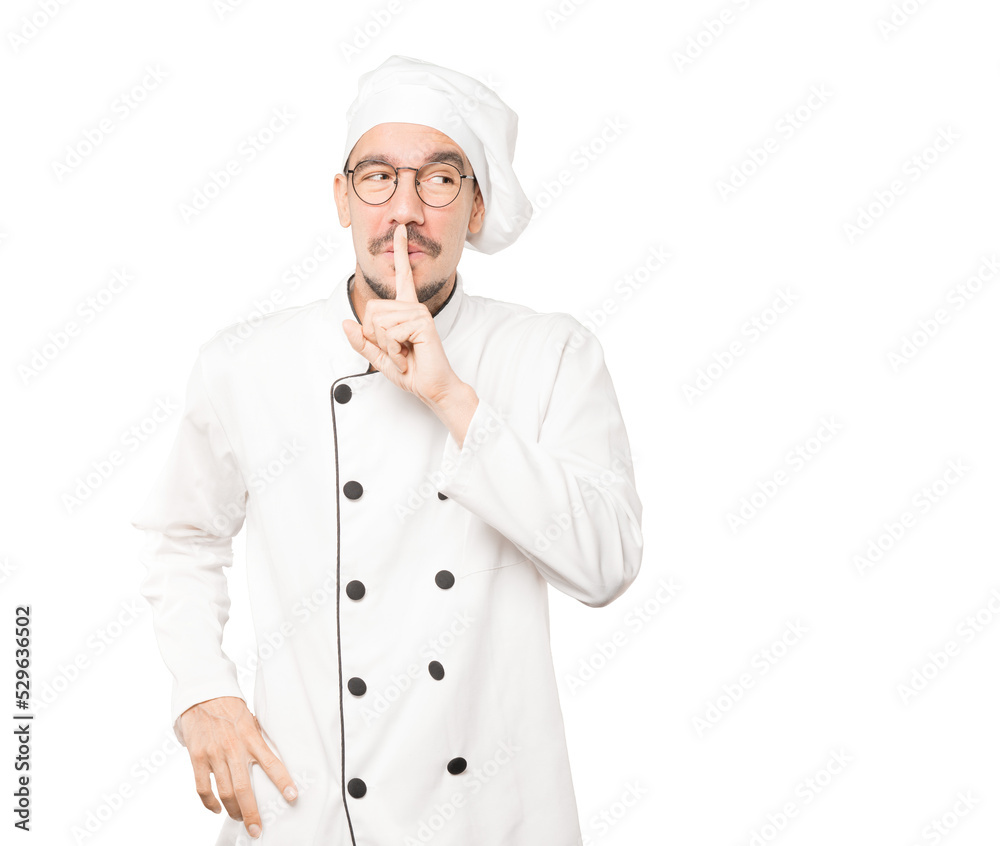 Amazed young chef asking for silence gesturing with his finger Amazed young chef asking for silence gesturing with his finger