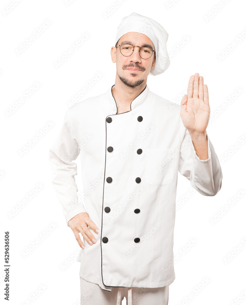 Happy young chef making a gesture of stop with his palm Happy young chef making a gesture of stop with his palm