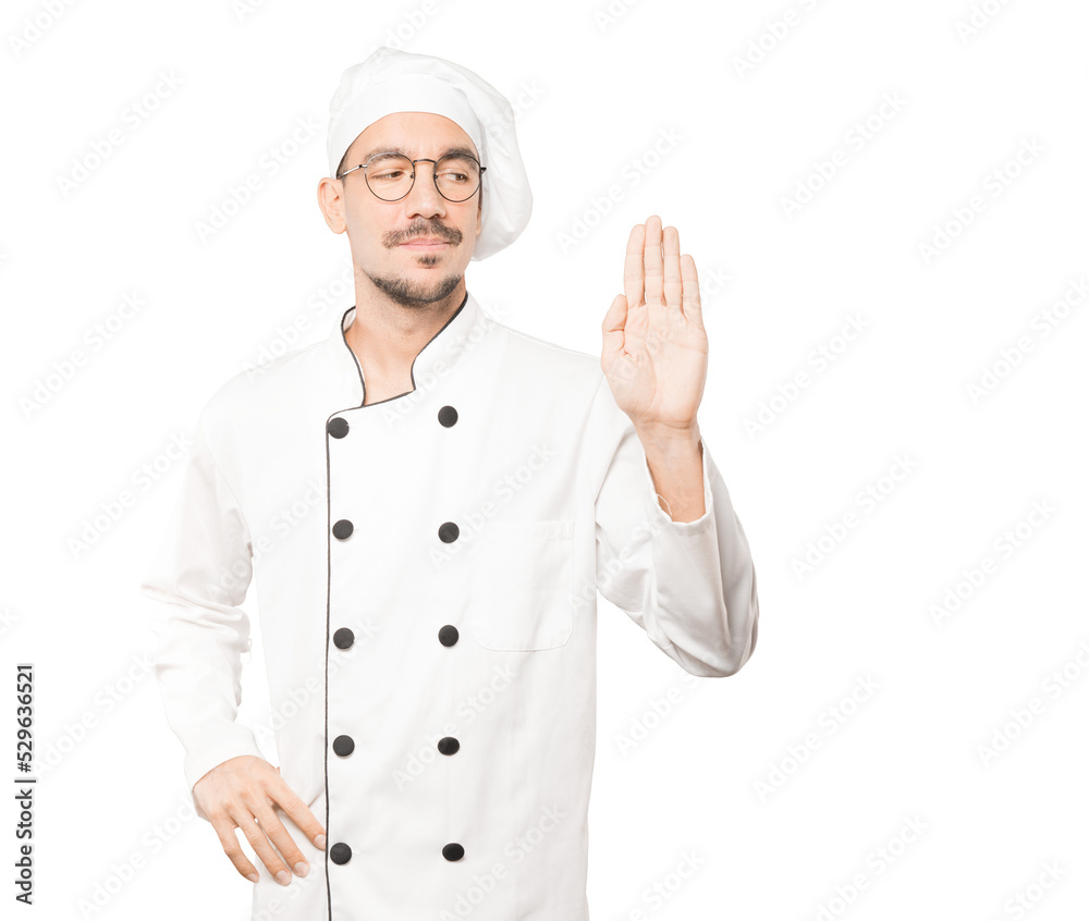 Happy young chef making a gesture of stop with his palm Happy young chef making a gesture of stop with his palm