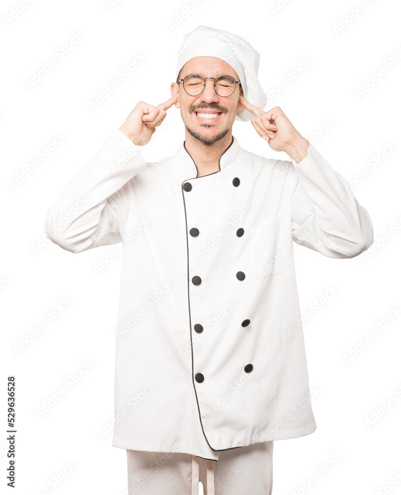 Young chef worried about loud noises and covering his ears Young chef worried about loud noises and covering his ears