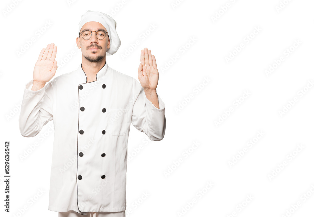 Serious young chef making a gesture of stop with his palm Serious young chef making a gesture of stop with his palm