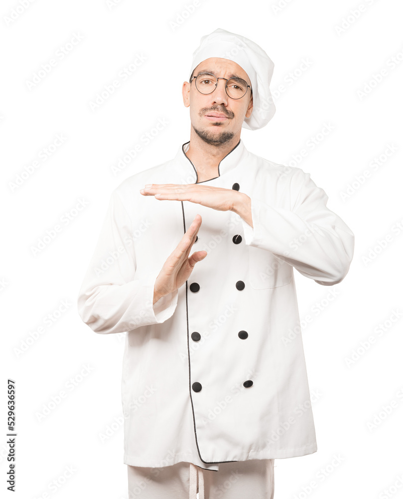 Friendly young chef making a time out gesture with his hands Friendly young chef making a time out gesture with his hands