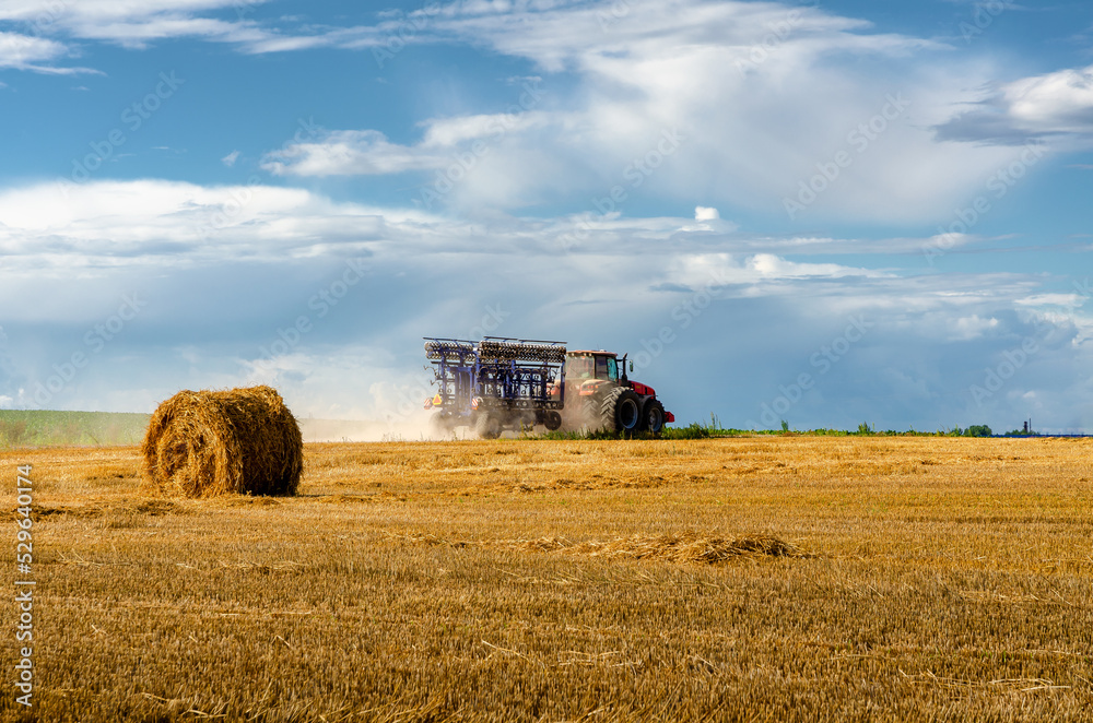 Fototapeta premium tractor field harvest wheat rolls sky beautiful view clouds summer season hay straw agriculture harvesting