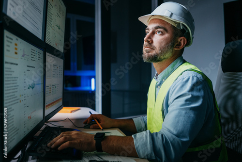 Bearded operator of factory control industry process using monitors. Engineer follow on production line
