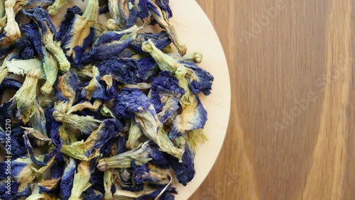 Rotating Dried Butterfly Pea Flower Blue Tea Leaves on Wood Platform. Healthy organic sustainable lifestyle concept. Close up shot, Top view. photo