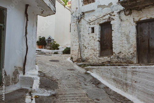 Fototapeta Naklejka Na Ścianę i Meble -  Narrow and colorful street in the village of Kritsa in the island of Crete. White street, beautiful traditional housing in Greece. 