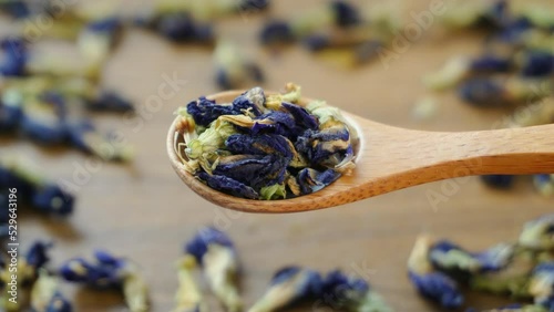 Wooden Spoon with Dried Butterfly Pea Flower Blue Tea Leaves Wood Background. Healthy organic sustainable lifestyle concept. Close up shot, Top view. photo