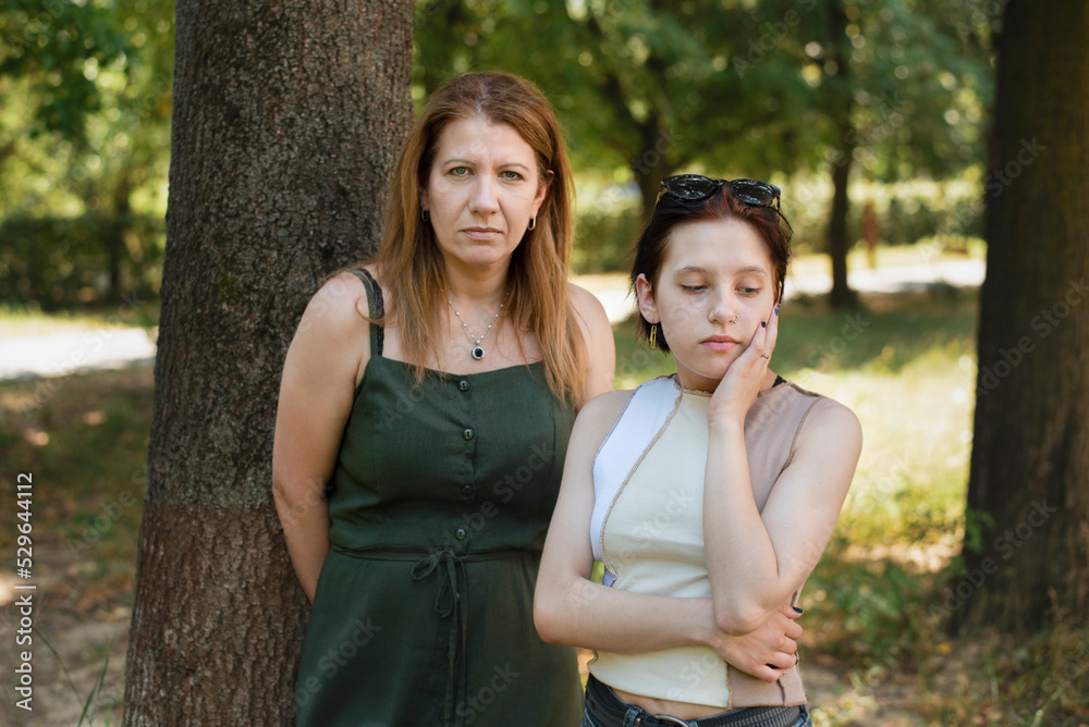 A teenage girl after talking with her mother looks away and thinks about her life, difficult relationship between daughter and mother, focus on the girl A teenage girl after talking with her mother looks away and thinks about her life, difficult relationship between daughter and mother, focus on the girl