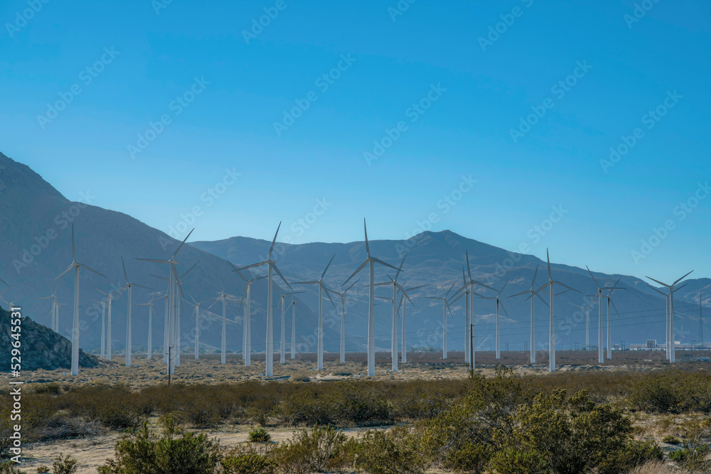 Wind park with windmills or wind turbines against mountains and blue sky Wind park with windmills or wind turbines against mountains and blue sky