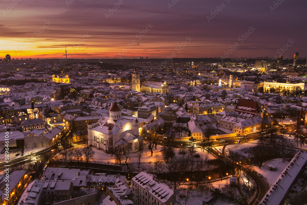 Naklejka premium Beautiful Vilnius city panorama in winter with snow covered houses, churches and streets. Aerial evening view. Winter city scenery in Lithuania.