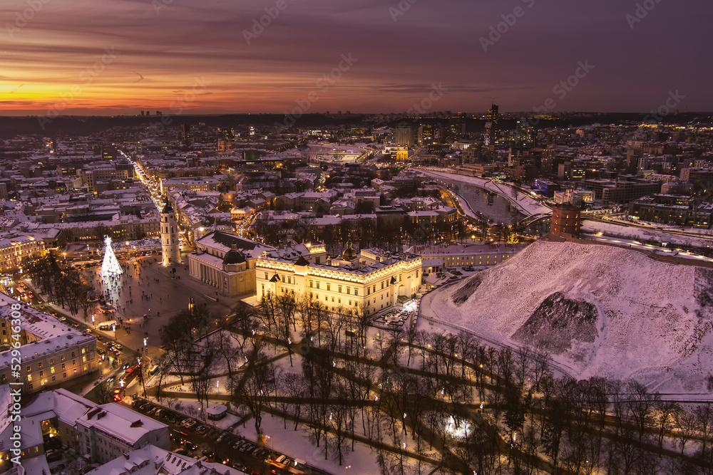 Beautiful Vilnius city panorama in winter with snow covered houses, churches and streets. Aerial evening view. Winter city scenery in Lithuania.