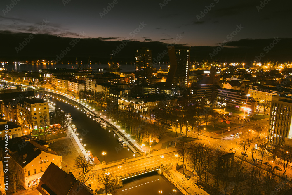 Aerial view of cityscape of Klaipeda at night. Yachts and boats docked along the embarkment of Dane river. Nightlife of Klaipeda, Lithuania.