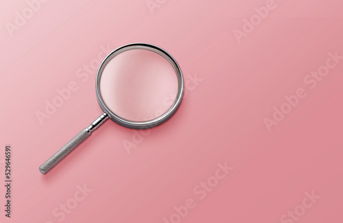 magnifying glass on pink background top view lying flat copy space concept