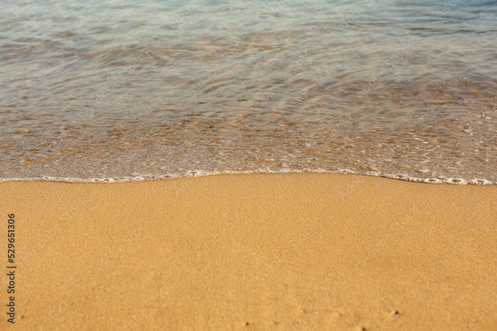 Background with golden sand on the coast of the island of Crete. Abstract surface with sand and clear sea water for text. Background with golden sand on the coast of the island of Crete. Abstract surface with sand and clear sea water for text.