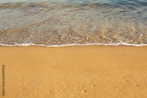 Background with golden sand on the coast of the island of Crete. Abstract surface with sand and clear sea water for text.