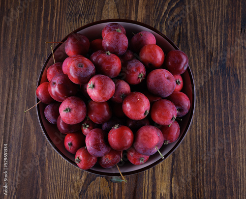 Full plate of fresh red apples on a wooden table. Top view.
