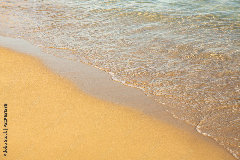 Background with golden sand on the coast of the island of Crete. Abstract surface with sand and clear sea water for text. Background with golden sand on the coast of the island of Crete. Abstract surface with sand and clear sea water for text.