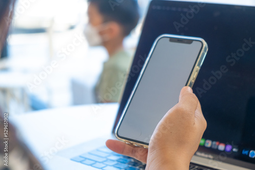 Business asian woman hand use smartphone with laptop communication sitting in cafe