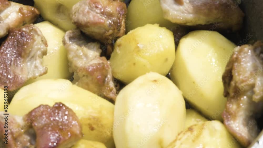 Meat is stewed with potatoes close-up. Fried meat with potatoes in the process of cooking. Meat with potatoes in a cauldron Meat is stewed with potatoes close-up. Fried meat with potatoes in the process of cooking. Meat with potatoes in a cauldron