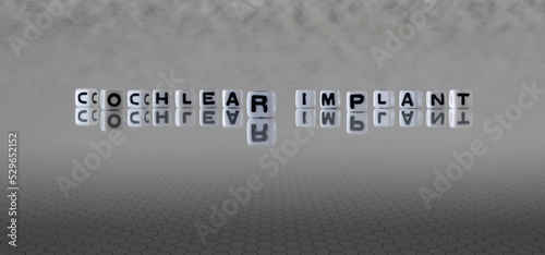 cochlear implant word or concept represented by black and white letter cubes on a grey horizon background stretching to infinity
