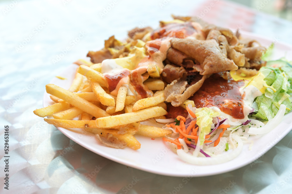 Doner kebab on a plate with French fries, salad and various sauces on a plate, popular fast food from Turkish cuisine, copy space, selected focus Doner kebab on a plate with French fries, salad and various sauces on a plate, popular fast food from Turkish cuisine, copy space, selected focus
