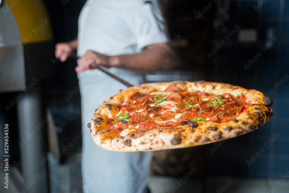 Pizzaiolo holding  pizza