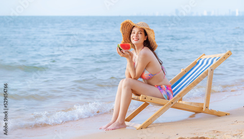 Sexy beautiful woman wearing bikini with beach hat show happy with eating water melon fruit on beach is holiday summer concept.