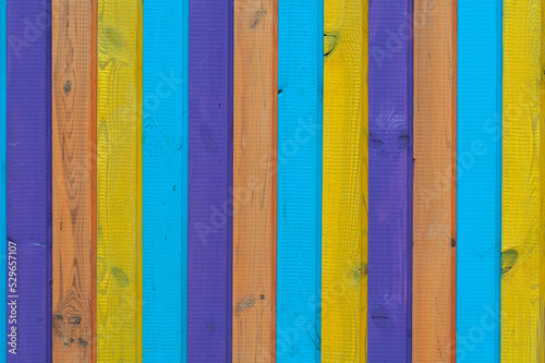 Background of vertical wooden boards painted in different colors, rough surface close-up.