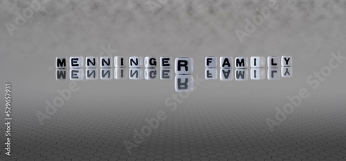 menninger family word or concept represented by black and white letter cubes on a grey horizon background stretching to infinity