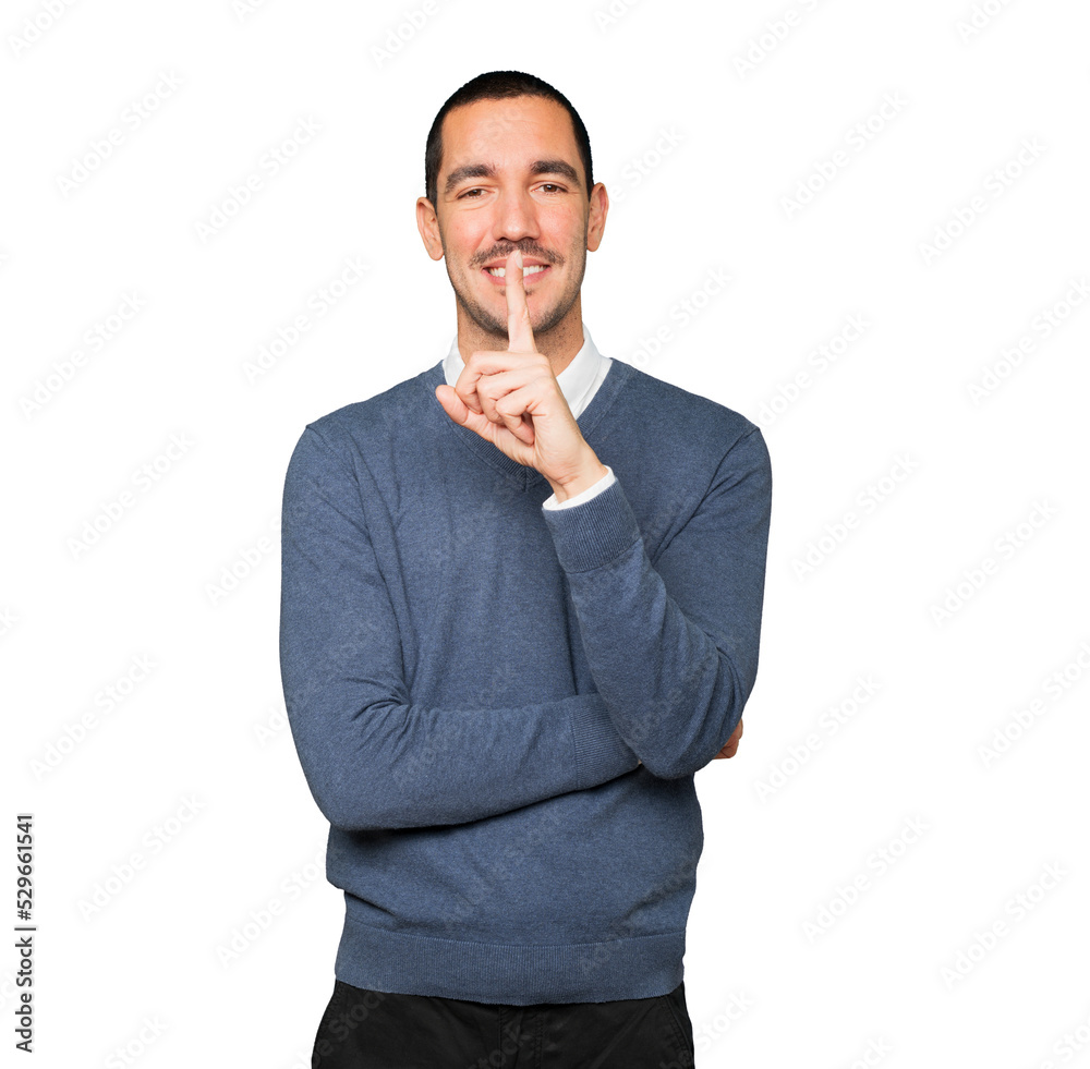 Happy young man asking for silence gesturing with his finger Happy young man asking for silence gesturing with his finger
