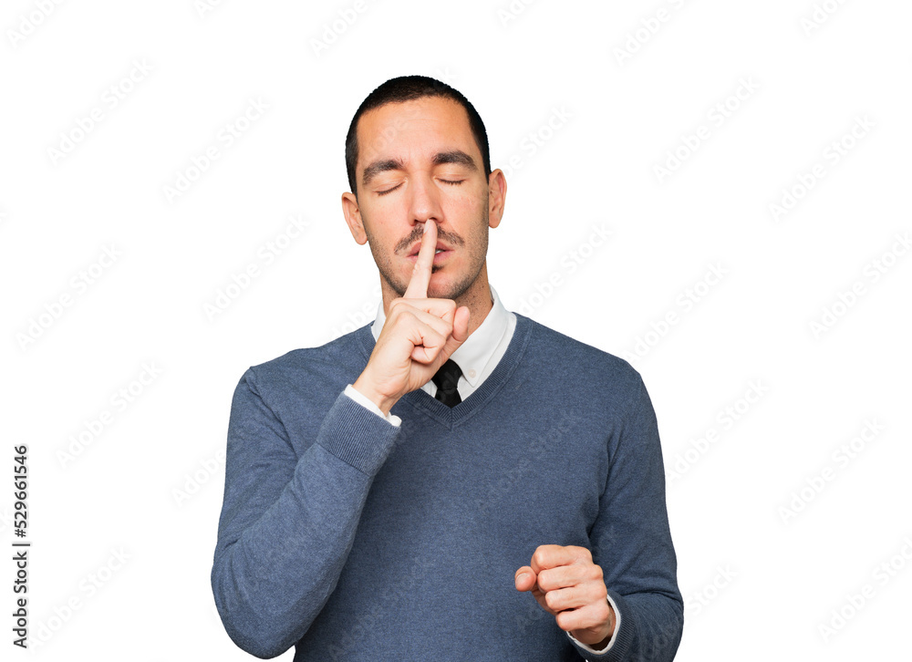 Serious young man asking for silence gesturing with his finger Serious young man asking for silence gesturing with his finger
