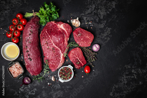 raw cuts of raw beef meat steaks on dark background, banner, menu, recipe place for text, top view