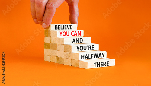 You can symbol. Concept words Believe you can and you are halfway there on wooden blocks on a beautiful orange table orange background. Businessman hand. Business motivational and you can concept. photo