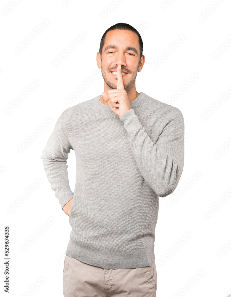 Happy young man asking for silence gesturing with his finger Happy young man asking for silence gesturing with his finger