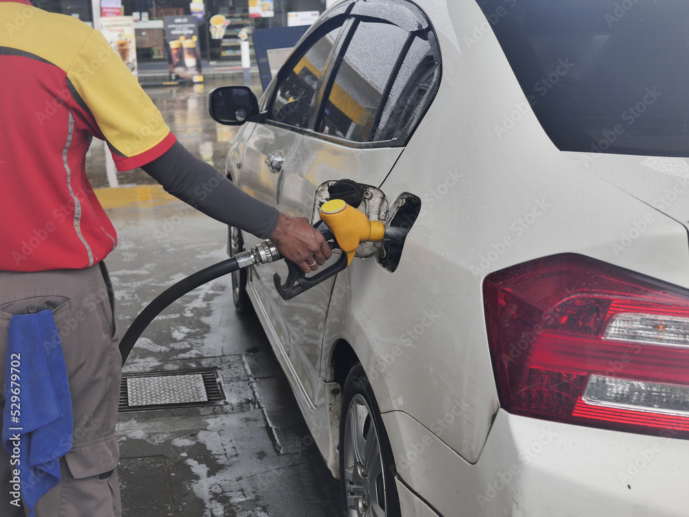 Dispenser pumping in car at gas station. Hand holding yellow fuel pump nozzle and refilling car. Woman refueling car at self service gas station. Hand refilling the car with fuel, focus hand. Dispenser pumping in car at gas station. Hand holding yellow fuel pump nozzle and refilling car. Woman refueling car at self service gas station. Hand refilling the car with fuel, focus hand.