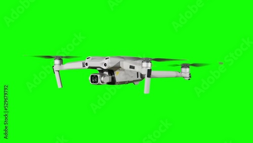 Real quadcopter with camera flights on a green screen. A drone hovering in the air with an alpha channel. Isolated portable copter on alpha matte. Aircraft blades rotate in hanging. Alpha channel 4K photo