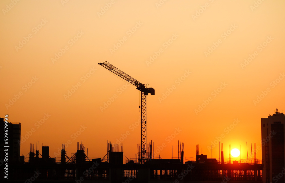 Obraz premium Sunset over Building construction in the city. Crane and structure silhouettes